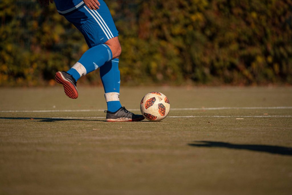 una persona pateando un balón de fútbol en un campo