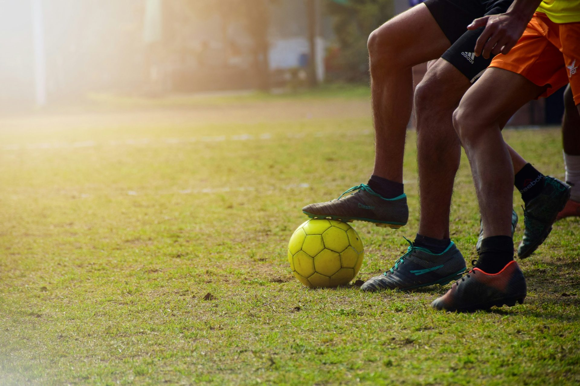 Hombre con pantalones cortos negros y un balón de fútbol Nike negro en un campo de césped verde durante el día.